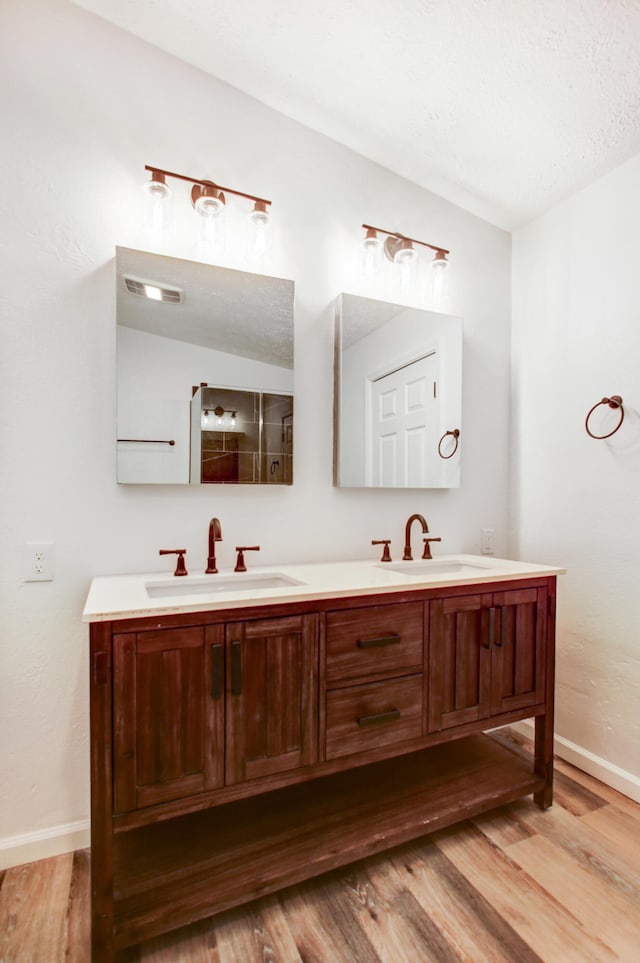 bathroom featuring double vanity, baseboards, a sink, and wood finished floors