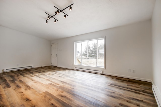 unfurnished room with a baseboard heating unit, baseboard heating, and wood finished floors