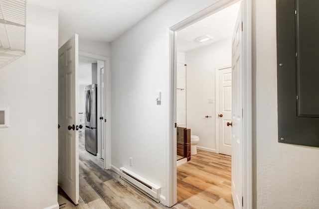 hallway featuring a baseboard heating unit, light wood-type flooring, electric panel, and baseboards