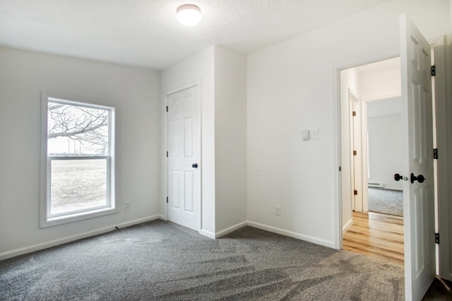 unfurnished bedroom featuring a textured ceiling, baseboard heating, carpet flooring, and baseboards