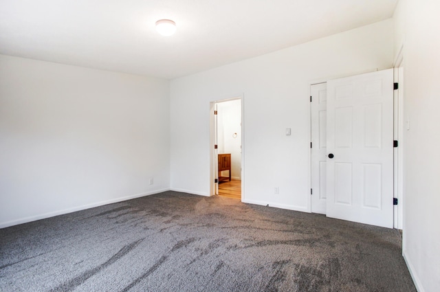 unfurnished bedroom featuring carpet floors, ensuite bath, and baseboards