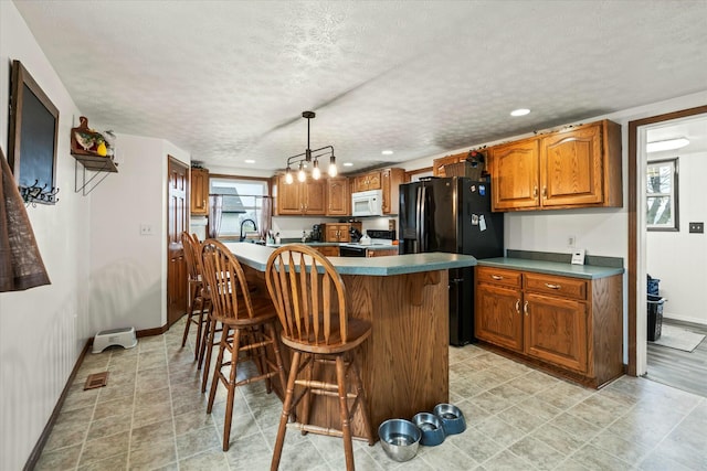 kitchen with black appliances, a textured ceiling, a kitchen breakfast bar, brown cabinets, and a center island