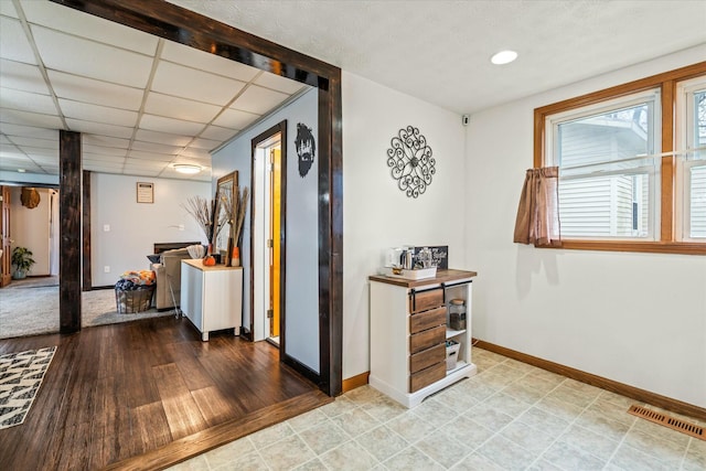 hallway with baseboards, visible vents, and a paneled ceiling