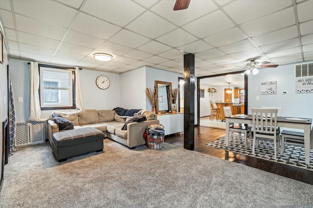 living area with a drop ceiling, visible vents, wood finished floors, and ceiling fan