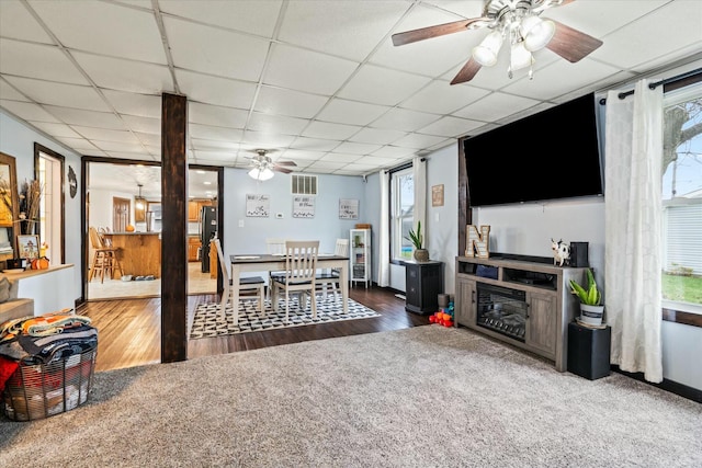 living area featuring a wealth of natural light, wood finished floors, and a drop ceiling