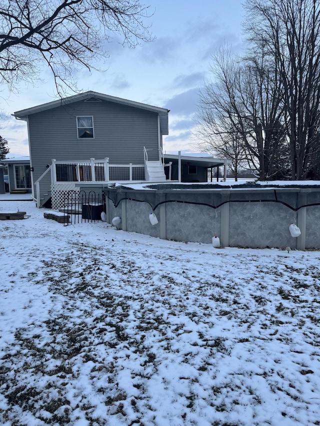 snow covered back of property with a wooden deck