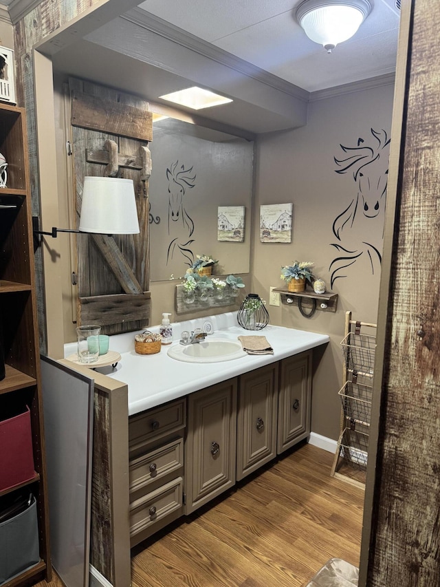 bathroom featuring ornamental molding, wood finished floors, and vanity