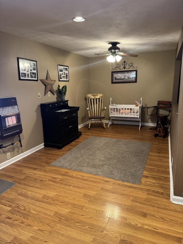 interior space featuring heating unit, a textured ceiling, baseboards, and wood finished floors