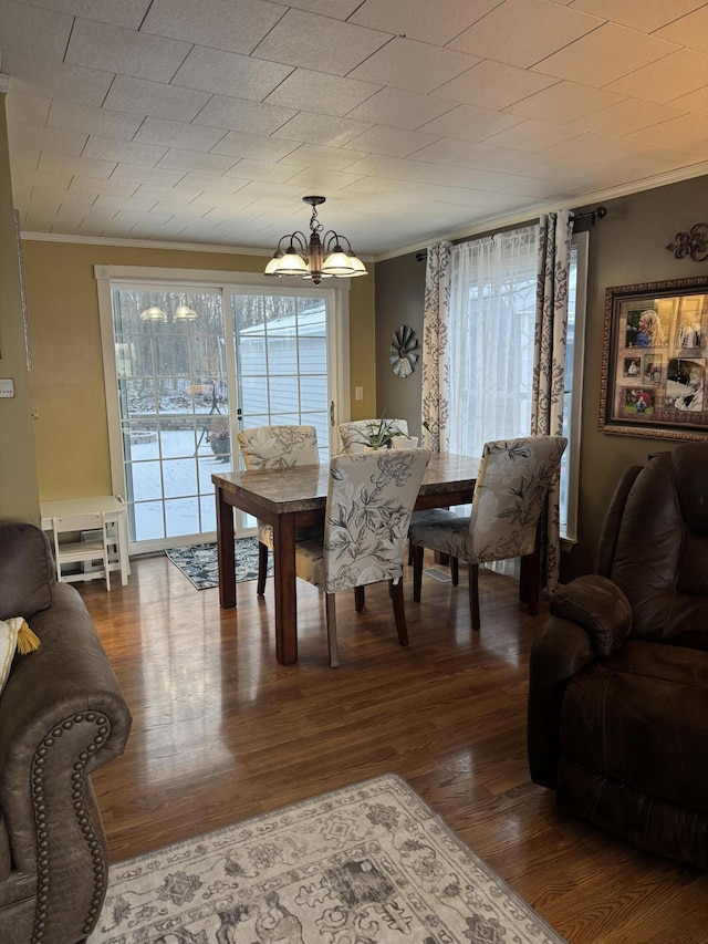 dining space featuring ornamental molding, a healthy amount of sunlight, dark wood-style floors, and an inviting chandelier