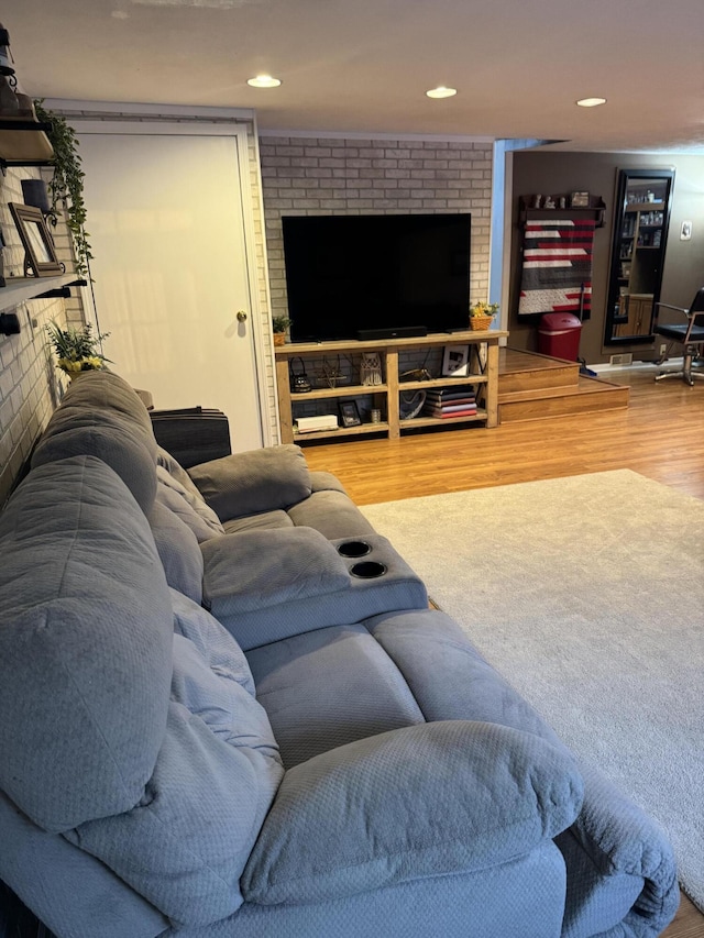 living room with a brick fireplace, wood finished floors, and recessed lighting