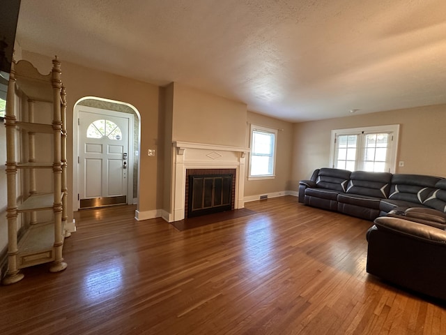 living room featuring dark hardwood / wood-style flooring, a fireplace, and a textured ceiling