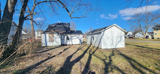 back of house with a lawn and a storage unit