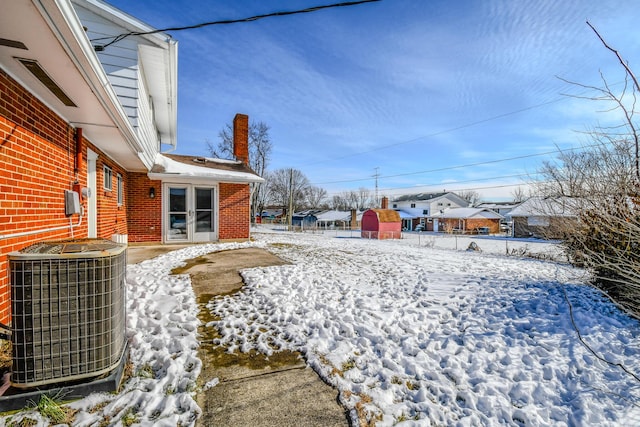 yard layered in snow with a storage shed and central AC unit