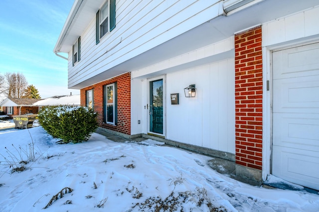 snow covered property entrance with brick siding