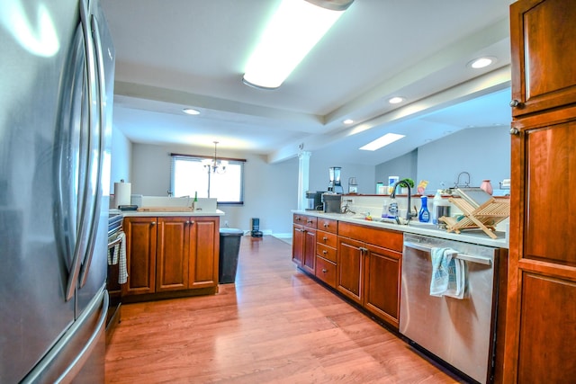 kitchen with stainless steel appliances, hanging light fixtures, brown cabinetry, and a peninsula