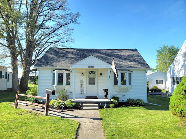 bungalow with covered porch, roof with shingles, and a front yard