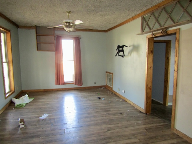 empty room featuring baseboards, a ceiling fan, wood finished floors, crown molding, and a textured ceiling