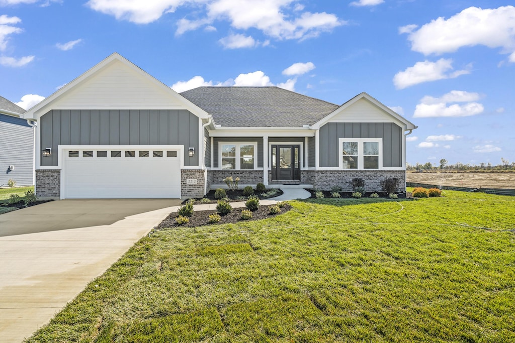 view of front of house with a garage, board and batten siding, driveway, and a front lawn