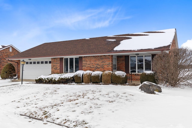 ranch-style house with brick siding, an attached garage, and roof with shingles