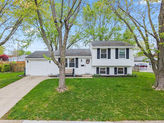 tri-level home featuring an attached garage, fence, driveway, and a front yard