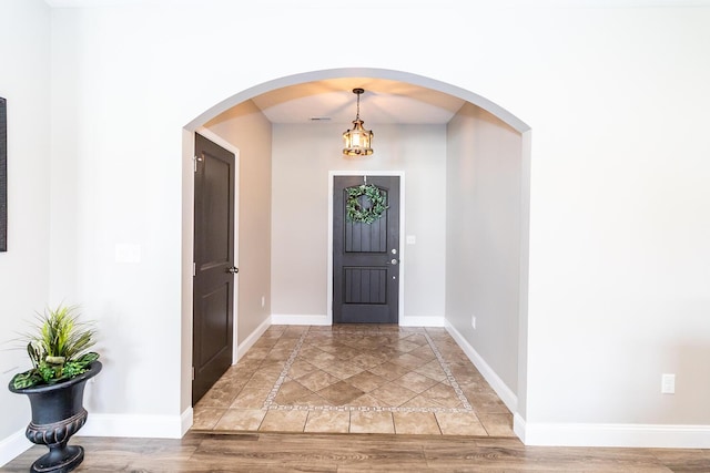 entrance foyer with arched walkways, visible vents, baseboards, and light wood-type flooring