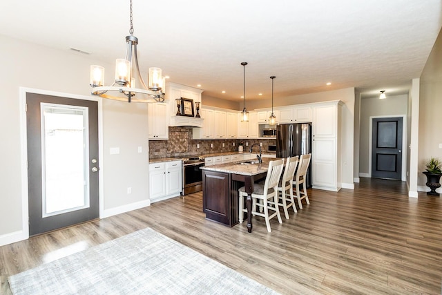 kitchen featuring a kitchen breakfast bar, an inviting chandelier, backsplash, a sink, and appliances with stainless steel finishes