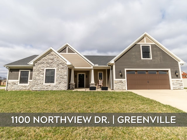 craftsman-style house with a front lawn, driveway, and stone siding