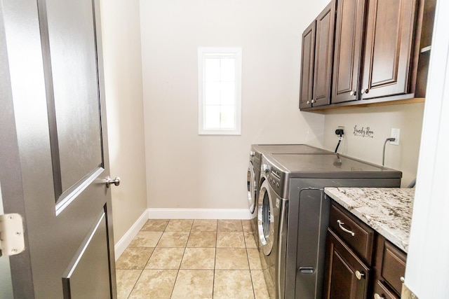 laundry area featuring light tile patterned flooring, baseboards, washing machine and dryer, and cabinet space