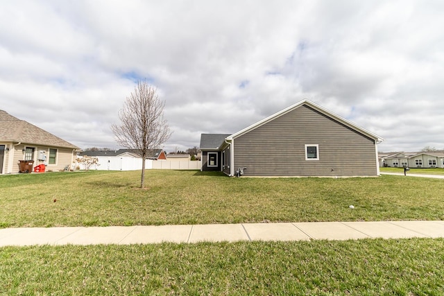 view of side of home with fence and a yard
