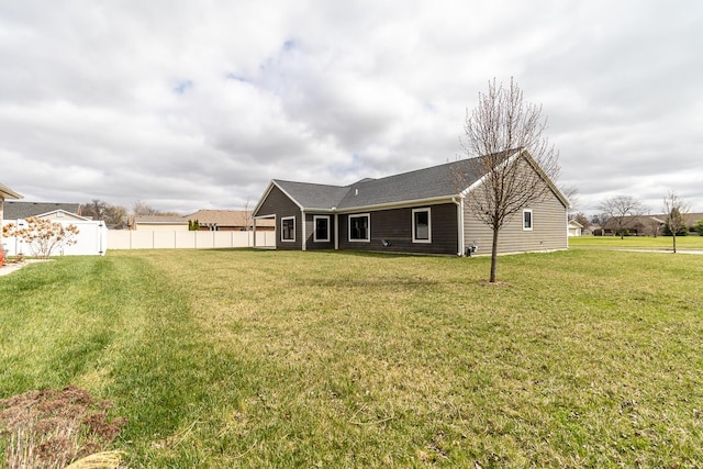 rear view of house with fence and a yard