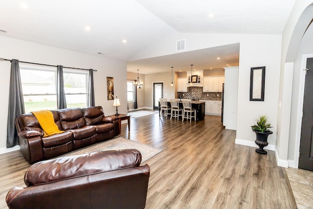 living area with visible vents, arched walkways, baseboards, and light wood-type flooring