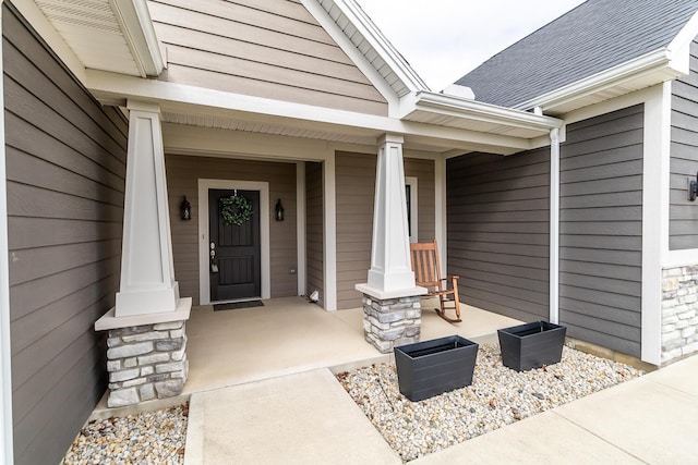 view of exterior entry featuring covered porch and stone siding