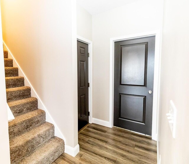entryway featuring baseboards, stairs, and wood finished floors