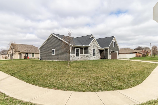 single story home with stone siding, a front yard, and a garage