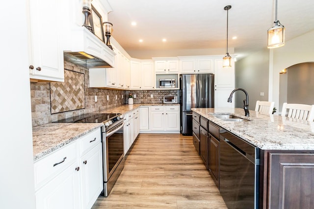 kitchen featuring arched walkways, white cabinetry, a sink, and appliances with stainless steel finishes