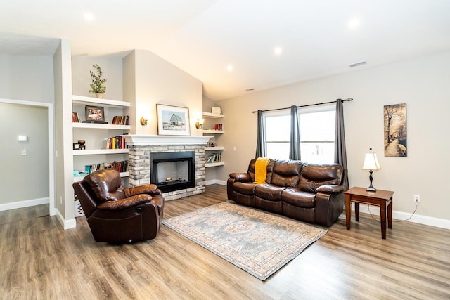 living area with lofted ceiling, baseboards, visible vents, a fireplace, and wood finished floors