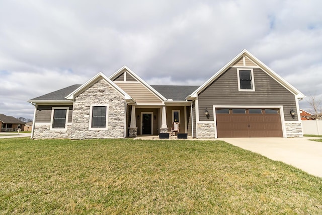 craftsman house with a front lawn, driveway, an attached garage, and stone siding