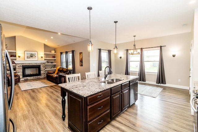 kitchen with appliances with stainless steel finishes, a breakfast bar area, light wood-style floors, and a sink