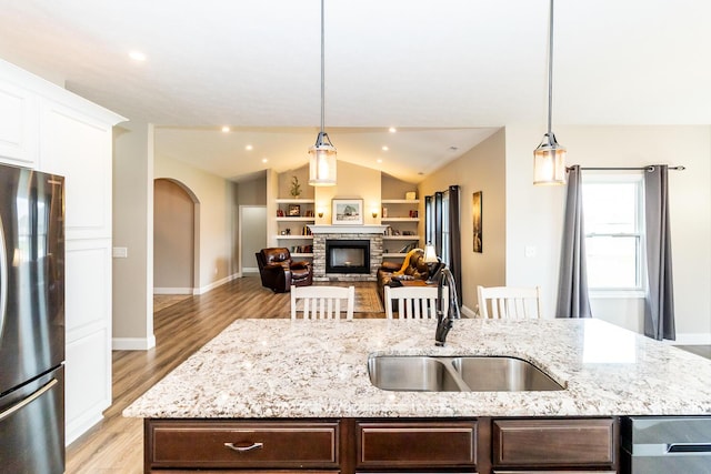 kitchen featuring light wood-style flooring, dark brown cabinets, lofted ceiling, a sink, and freestanding refrigerator