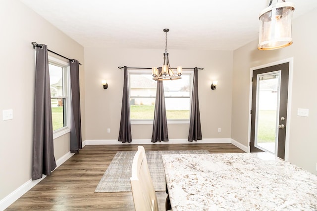 unfurnished dining area featuring an inviting chandelier, baseboards, and wood finished floors