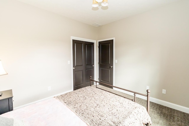 carpeted bedroom featuring baseboards and visible vents