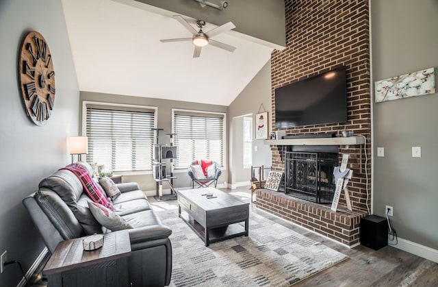 living area with beam ceiling, wood finished floors, baseboards, a brick fireplace, and ceiling fan