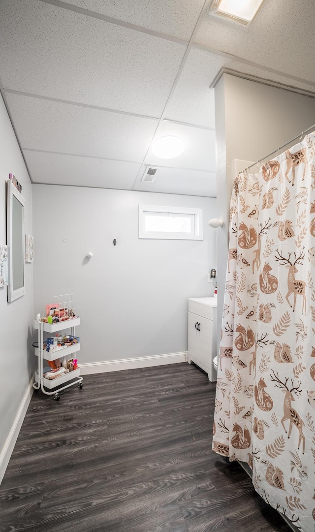 bathroom with visible vents, a paneled ceiling, baseboards, and wood finished floors