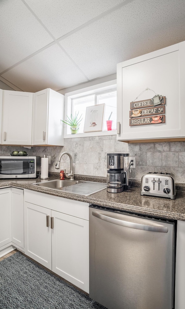 kitchen with a sink, stainless steel appliances, tasteful backsplash, and white cabinets