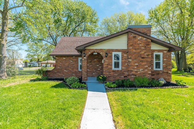 ranch-style home featuring fence, brick siding, and a front yard