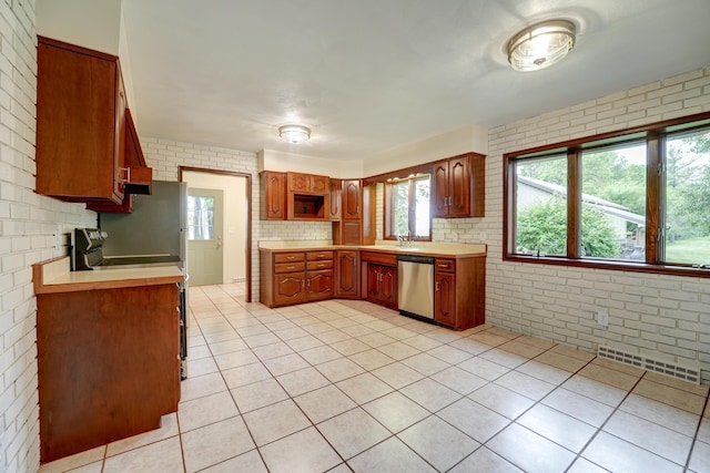 5341 Riffle Rd, Ansonia, OH 45303 - kitchen with stainless steel dishwasher, light countertops, light tile patterned floors, brick wall, and range