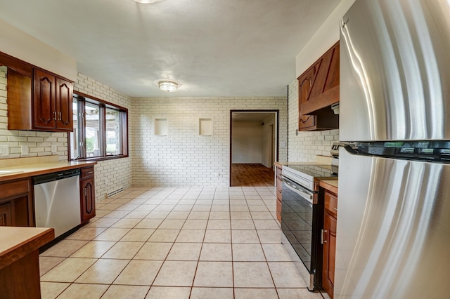 5341 Riffle Rd, Ansonia, OH 45303 - kitchen with appliances with stainless steel finishes, brick wall, decorative backsplash, light countertops, and light tile patterned floors