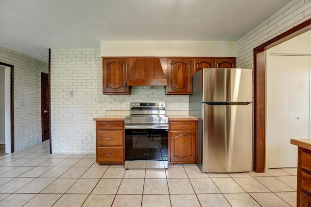 5341 Riffle Rd, Ansonia, OH 45303 - kitchen with appliances with stainless steel finishes, premium range hood, brick wall, light countertops, and light tile patterned floors