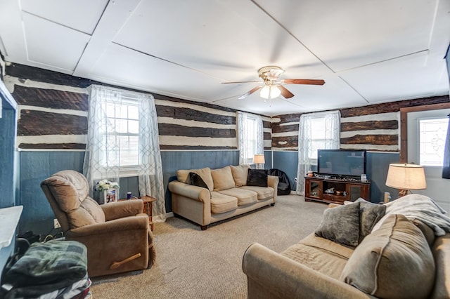 living room featuring rustic walls, ceiling fan, and carpet floors