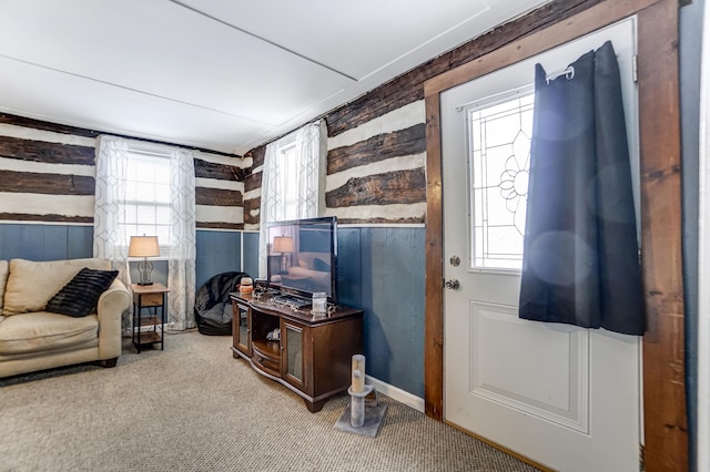 living room featuring wood walls, plenty of natural light, and light carpet